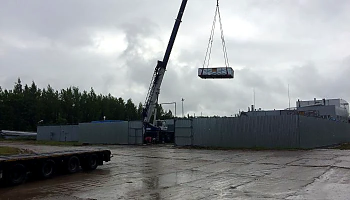 Автокран поднимает блок оборудования на промышленной площадке